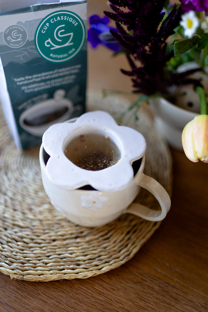 Handmade white ceramic tea strainer with floral cut-out design for loose leaf tea.