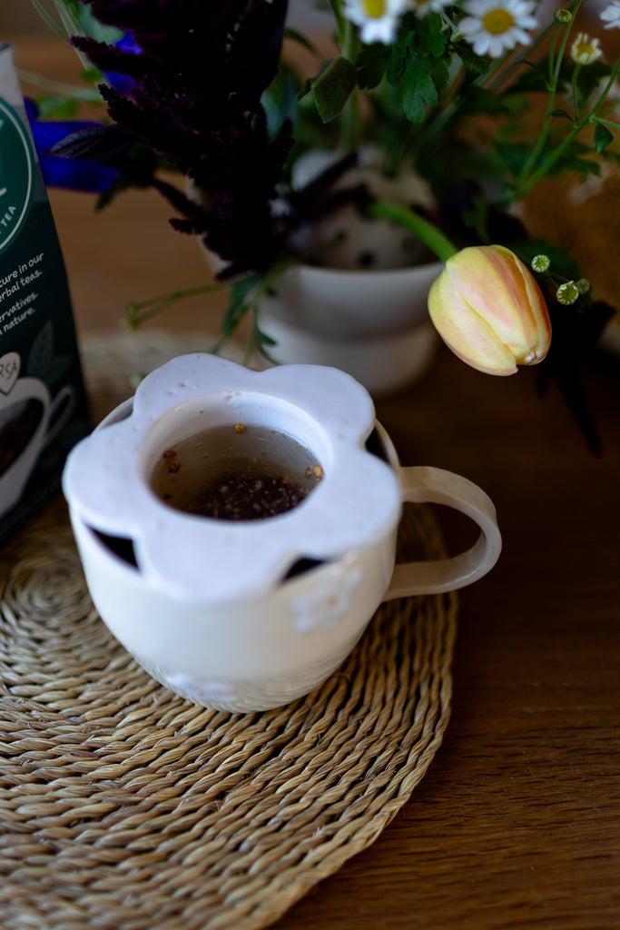 Handmade white ceramic tea strainer with floral cut-out design for loose leaf tea.