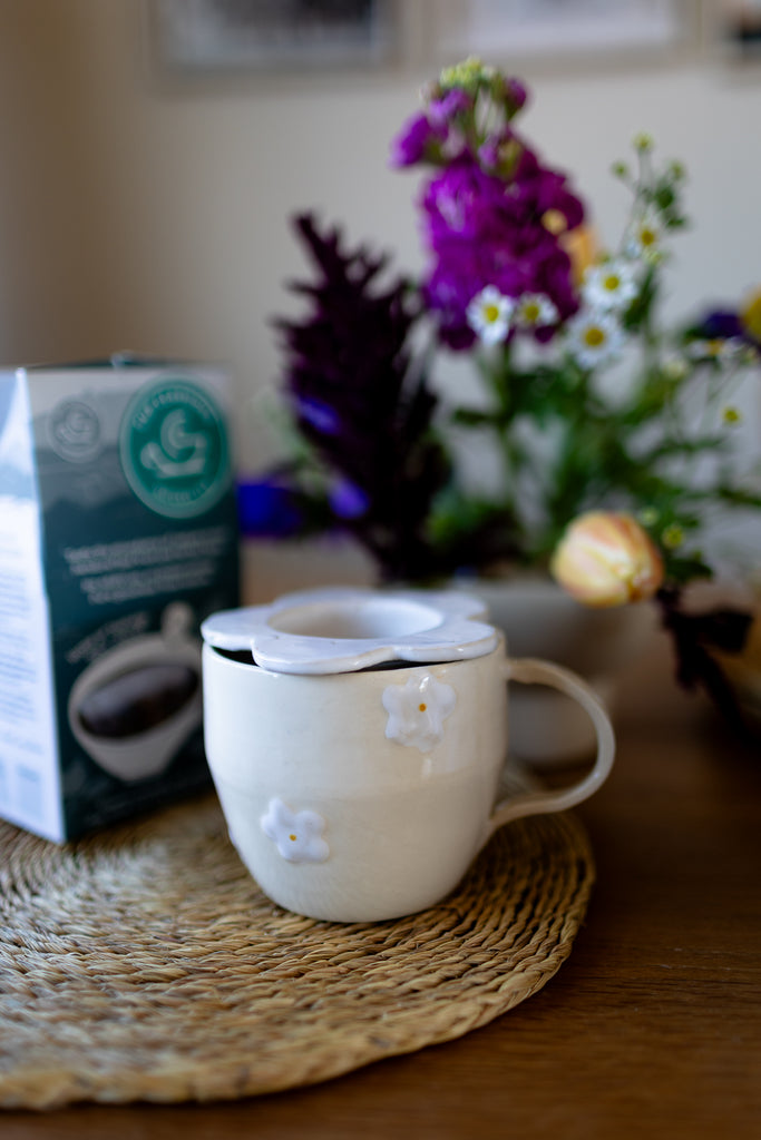 Handmade white ceramic tea strainer with floral cut-out design for loose leaf tea.