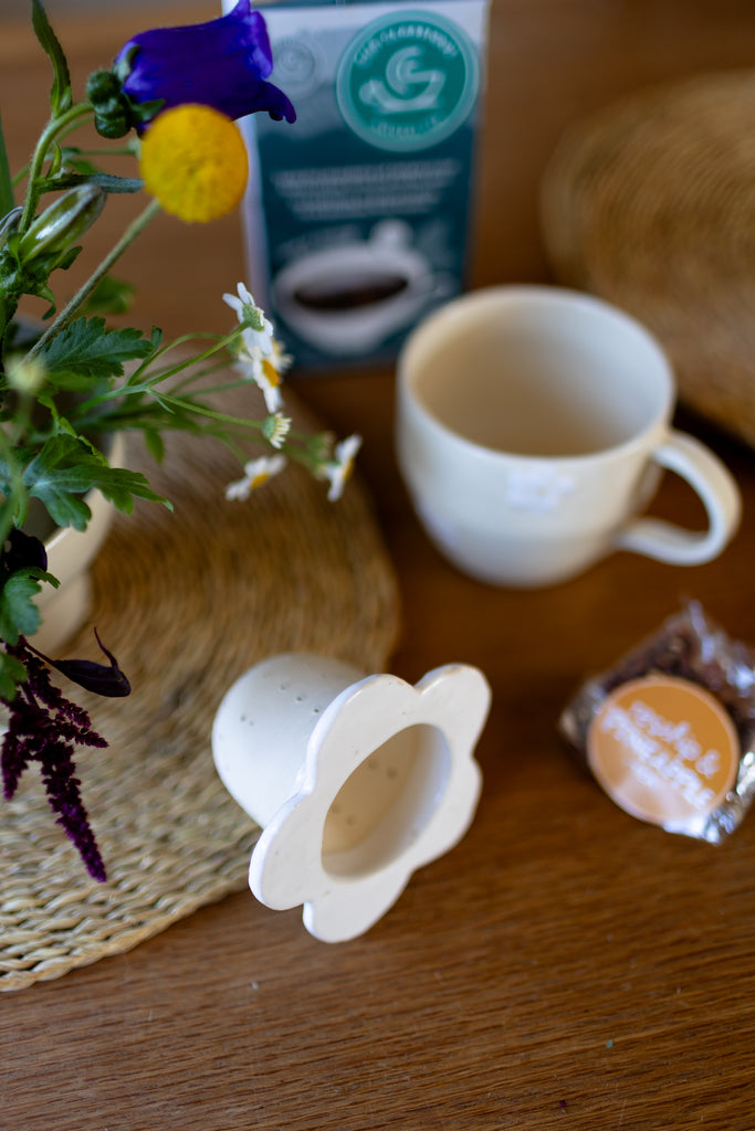 Handmade white ceramic tea strainer with floral cut-out design for loose leaf tea.