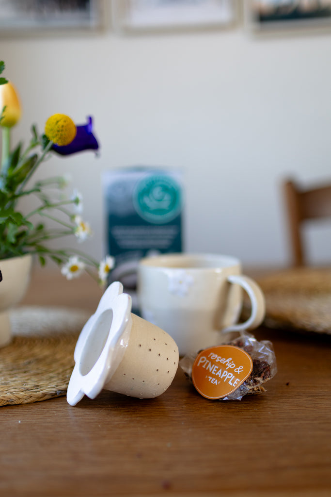 Handmade white ceramic tea strainer with floral cut-out design for loose leaf tea.