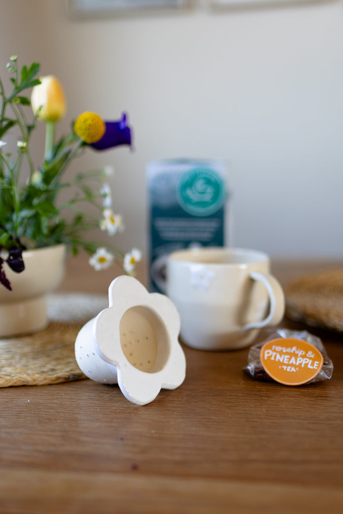 Handmade white ceramic tea strainer with floral cut-out design for loose leaf tea.