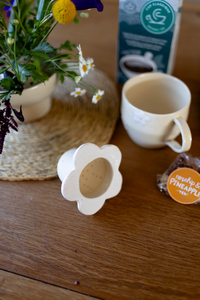 Handmade white ceramic tea strainer with floral cut-out design for loose leaf tea.