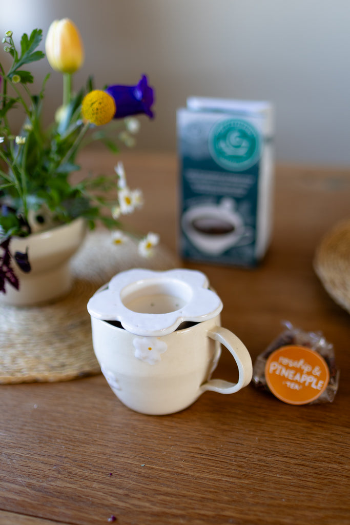 Handmade white ceramic tea strainer with floral cut-out design for loose leaf tea.