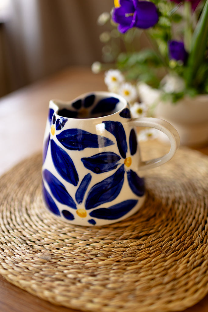 Handmade ceramic jug with blue daisy pattern, perfect as a milk jug or small vase.